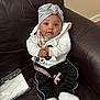 baby, child, infant, face, headband, clothing, jacket, pants, socks, couch, leather, indoors, pacifier_clip, seated, expression, cute, bundle, comfort, young, portrait
