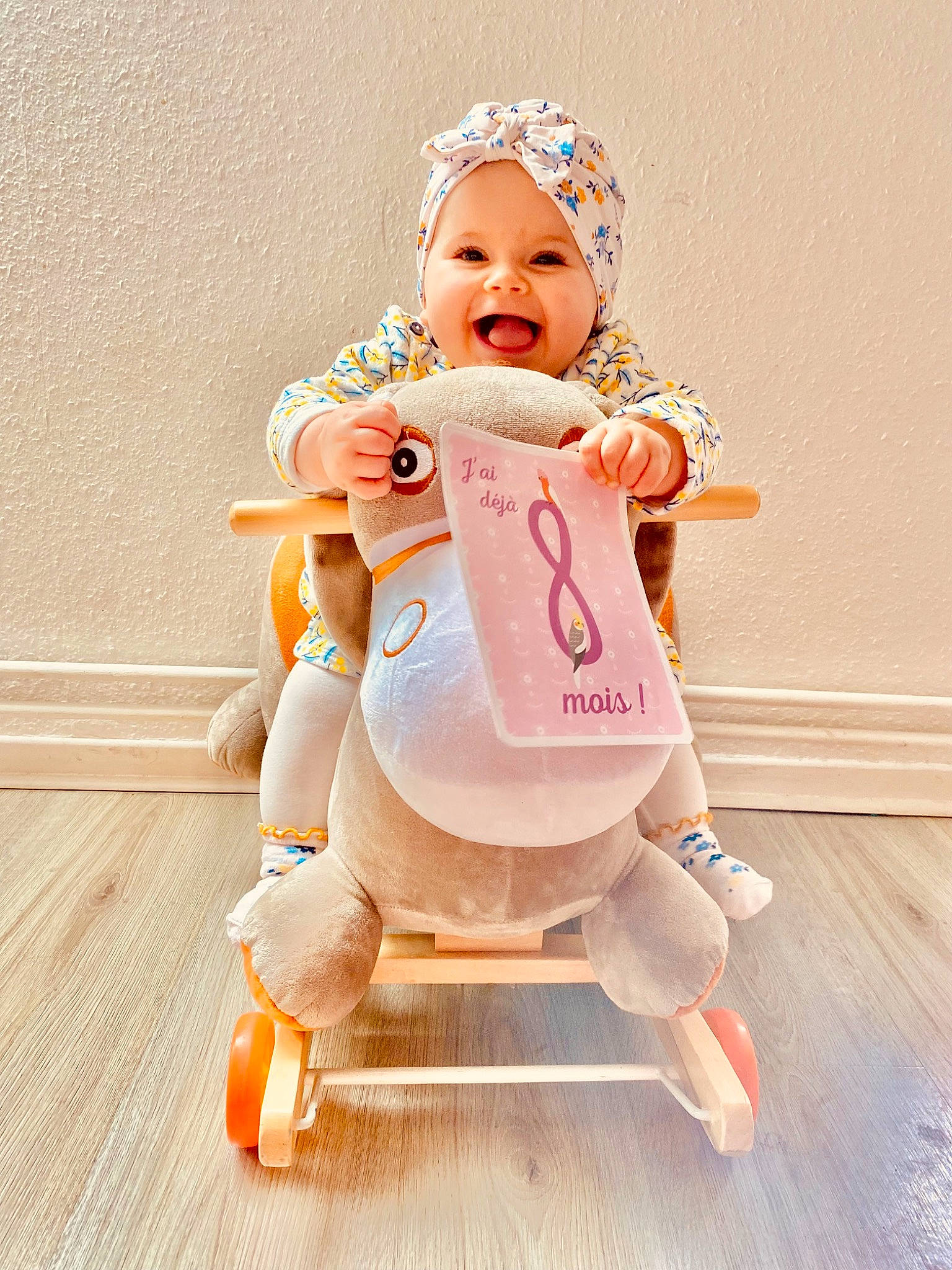 Luna participe au concours pour gagner de l'argent avec cette photo : arm, baby, baby_products, baby_toddler_clothing, child, comfort, costume, flooring, fun, happy, hardwood, headwear, human_leg, joy, knee, peach, person, personal_protective_equipment, sitting, smile