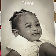 Breon joined the competition — help win amazing prizes! baby, infant, portrait, black_and_white, smile, child, toddler, curly_hair, white_shirt, face, expression, cute, lying_down, soft_background, close_up, young_child, happy, skin, head, eyes
