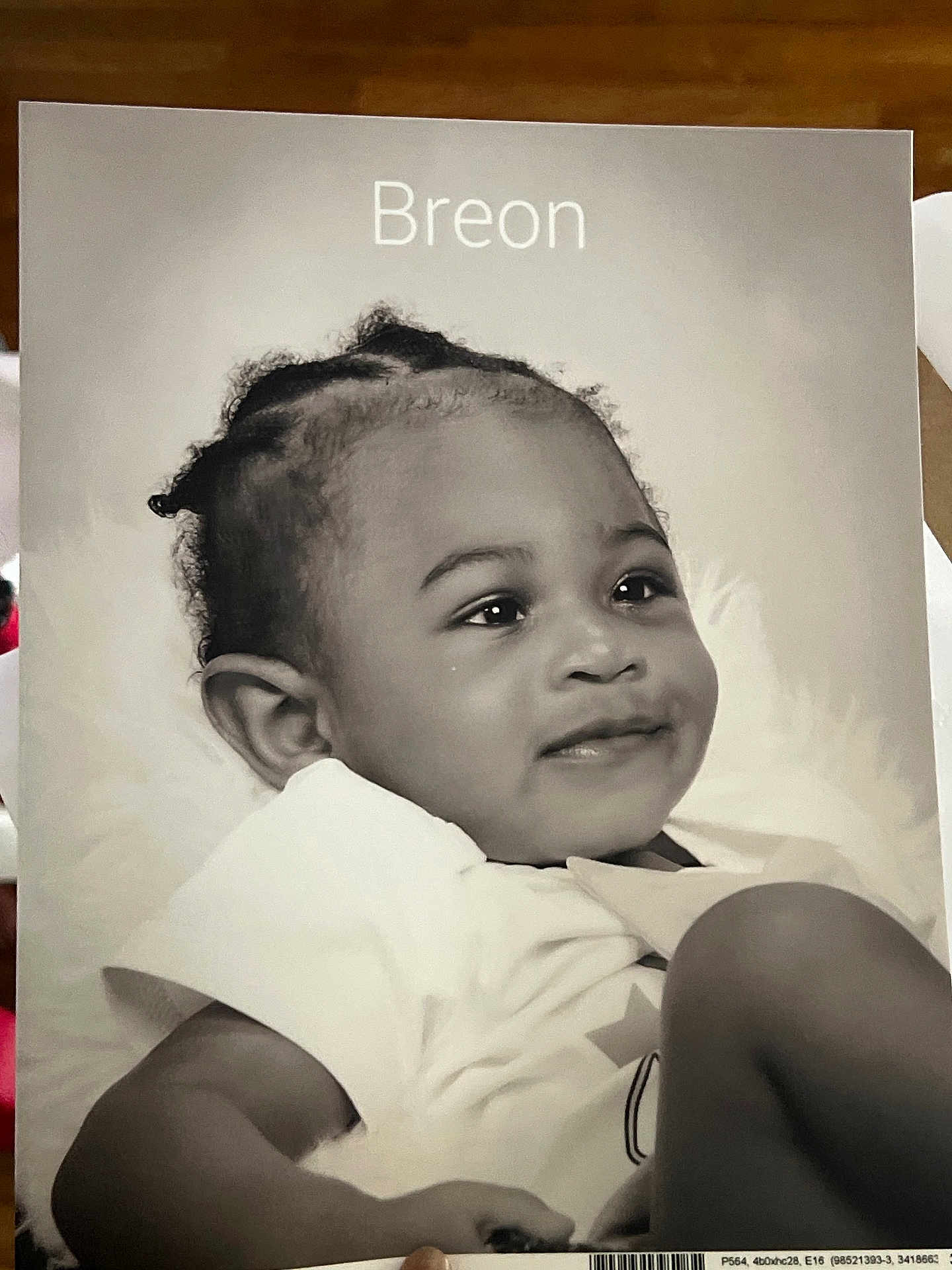 Breon joined the competition — help win amazing prizes! baby, infant, portrait, black_and_white, smile, child, toddler, curly_hair, white_shirt, face, expression, cute, lying_down, soft_background, close_up, young_child, happy, skin, head, eyes