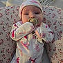 baby, infant, pacifier, onesie, hat, floral, cushion, blanket, sleepwear, cute, child, newborn, resting, soft, comfort, indoors, portrait, face, hand, clothing