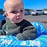baby, blue_sky, child, clothing, curious, cute, daylight, elephant_pattern, expression, face, green_sweater, infant, knitwear, outdoor, parking_lot, person, portrait, shopping_cart, soft_light, young_child