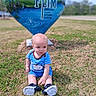 Tatem is registered to the contest to win money with this photo: baby, blue_outfit, casual_clothing, child, curious, daylight, field, grass, greenery, head, heart_shaped, nature, outdoor, person, portrait, sculpture, shoes, sitting, text, young_child