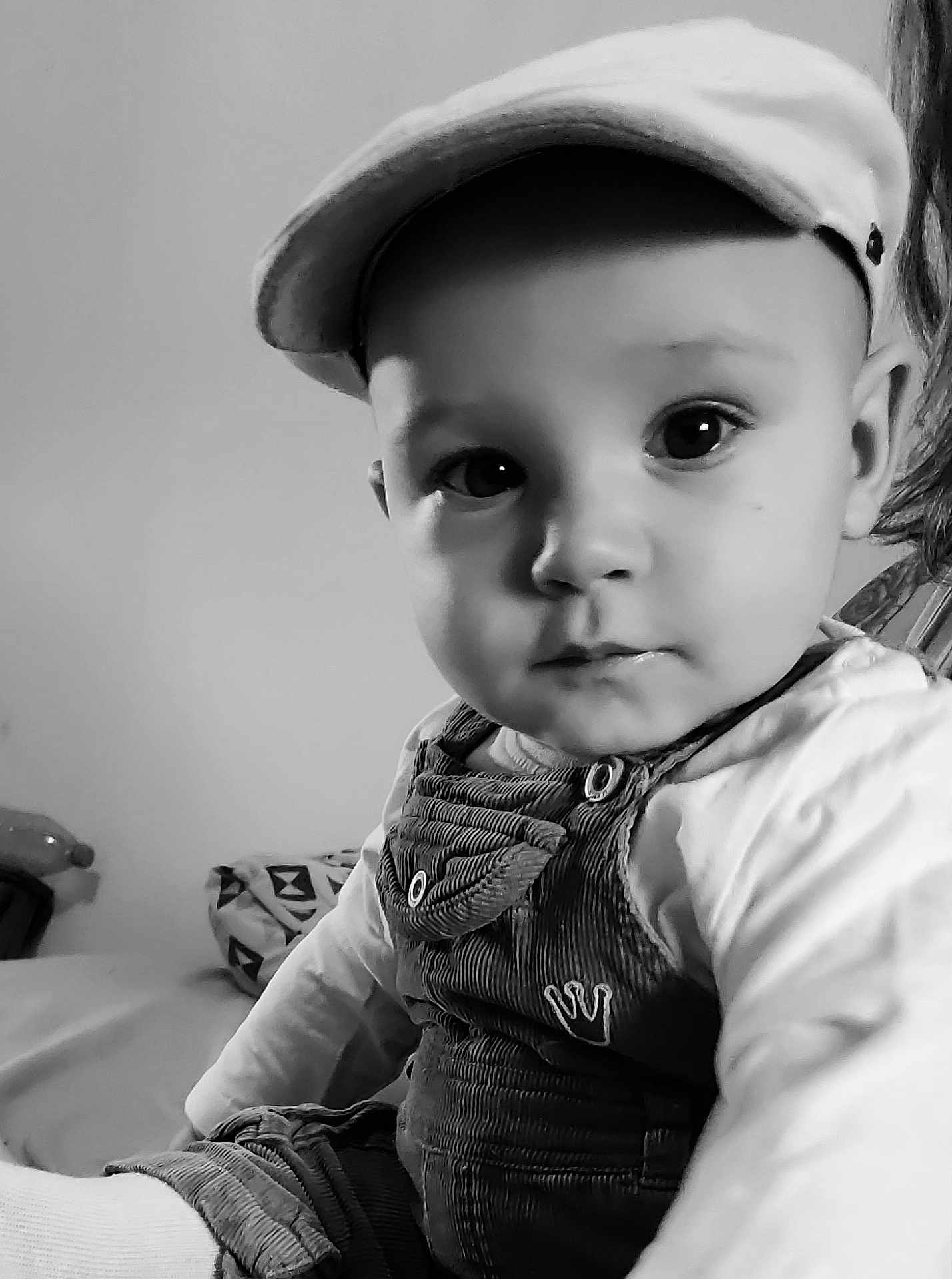 Lizio participe au concours pour gagner de l'argent avec cette photo : baby, child, infant, cap, overalls, portrait, black_and_white, indoor, cute, face, eyes, clothing, sitting, person, young, baby_clothes, headwear, closeup, curious, soft_light