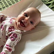 Lilly joined the competition — help win amazing prizes! baby, changing_pad, child, cute, eyes, face, floral_pattern, green_blanket, happy, head, indoors, infant, lying_down, mouth, onesie, person, portrait, skin, smiling, white