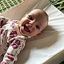 baby, changing_pad, child, cute, eyes, face, floral_pattern, green_blanket, happy, head, indoors, infant, lying_down, mouth, onesie, person, portrait, skin, smiling, white