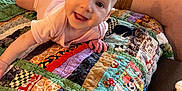 Lilly is registered to the contest to win money with this photo: adult, baby, casual_clothing, child, colorful, couch, fabric, hand, happy, home, indoor, infant, legs, patchwork_quilt, person, playful, portrait, relaxed, smiling, textile