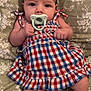 baby, infant, pacifier, dress, plaid, pattern, blanket, floral, cute, child, skin, face, legs, lying_down, indoors, fabric, comfort, small_hands, newborn, resting
