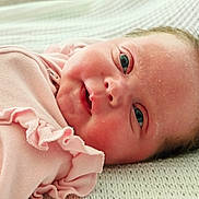 Sienna is registered to the contest to win money with this photo: baby, newborn, infant, pink_clothing, ruffles, blanket, face, skin, eyes, closeup, lying_down, soft_texture, cute, child, portrait, indoors, young, person, sleepwear, resting