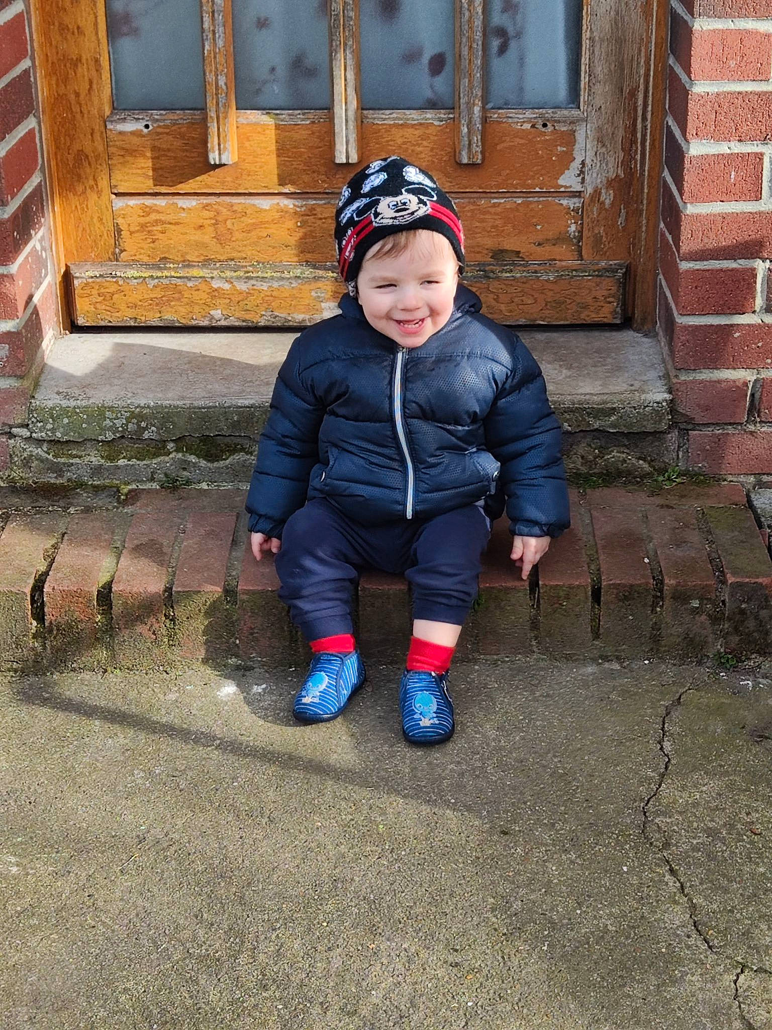 Raphaël participe au concours pour gagner de l'argent avec cette photo : baby_toddler_clothing, beanie, boot, brick, brickwork, cap, child, cobblestone, flooring, grass, happy, headwear, jacket, joy, people_in_nature, person, road_surface, smile, snapshot, toddler