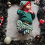 baby, newborn, sleeping_baby, elf_outfit, striped_pajamas, christmas, tinsel, ornament, candy_cane, gift, knit_blanket, festive, holiday, hat, socks, closeup, portrait, cozy, cute, tiny