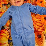 Mateo joined the competition — help win amazing prizes! baby, child, smiling, blue_onesie, pumpkin, sunflower, autumn, blanket, happy, cute, infant, face, lying_down, fall, seasonal, cozy, portrait, person, orange, yellow