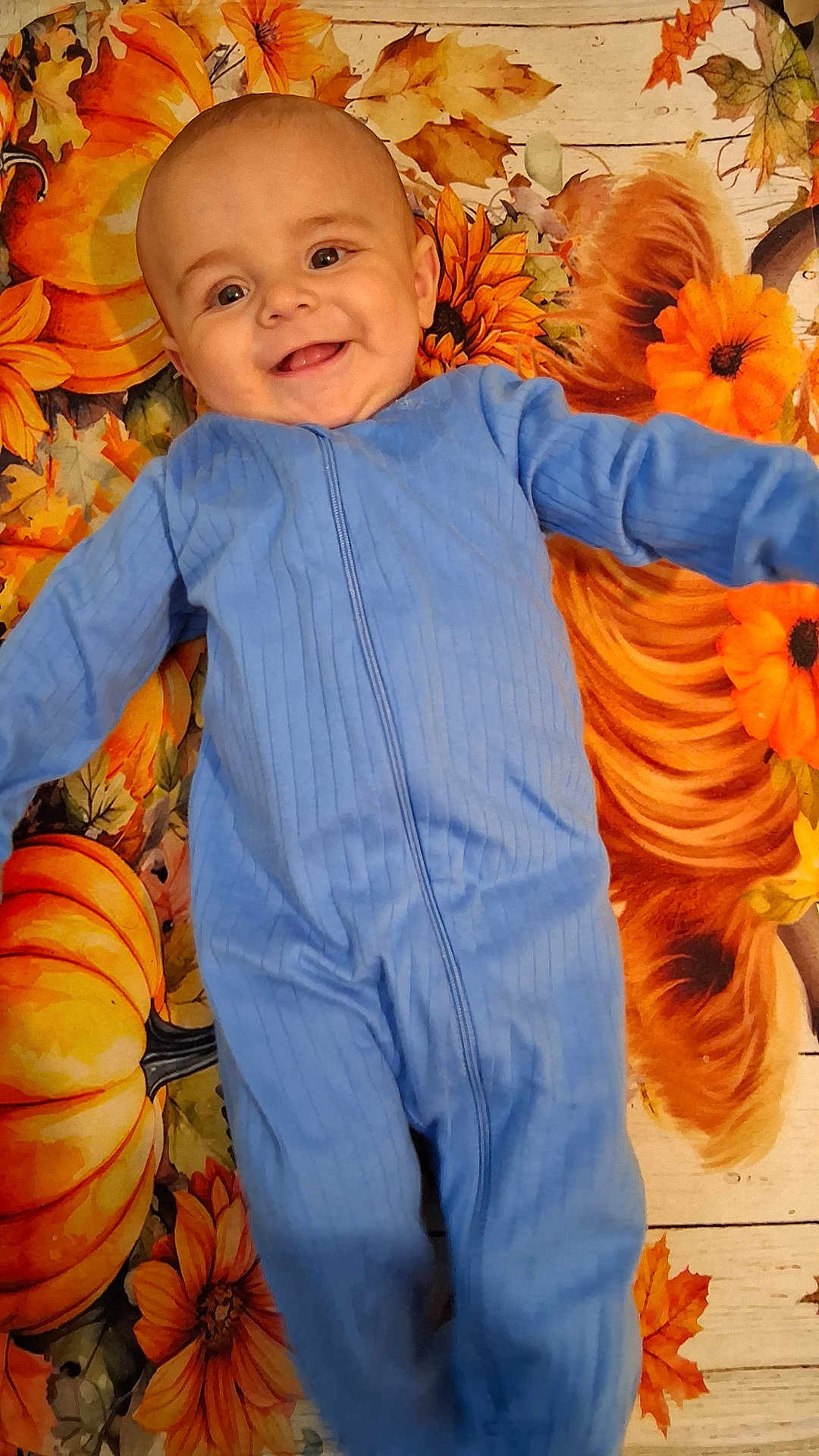 Mateo joined the competition — help win amazing prizes! baby, child, smiling, blue_onesie, pumpkin, sunflower, autumn, blanket, happy, cute, infant, face, lying_down, fall, seasonal, cozy, portrait, person, orange, yellow