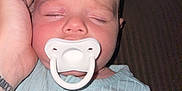 Waylon Blake is registered to the contest to win money with this photo: baby, sleeping, pacifier, hand, tattoo, onesie, ribbed_clothing, indoors, closeup, child, infant, peaceful, cute, face, skin, person, resting, toddler, newborn, portrait