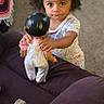 Neena is registered to the contest to win money with this photo: child, doll, indoor, carpet, toys, couch, curly_hair, person, playtime, living_room, cute, expression, holding, small, young, curiosity, furniture, home, casual_clothing, floor