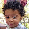 toddler, child, curly_hair, headband, mouse_ears, pink, white, floral_clothing, outdoor, portrait, close_up, cute, baby, person, young_child, face, expression, earrings, soft_lighting, background_blur