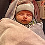 baby, sleeping, hat, pom_pom, blanket, bear_design, car_seat, warning_label, cozy, child, infant, face, closed_eyes, warm, soft_texture, cute, bundle, headwear, rest, comfort