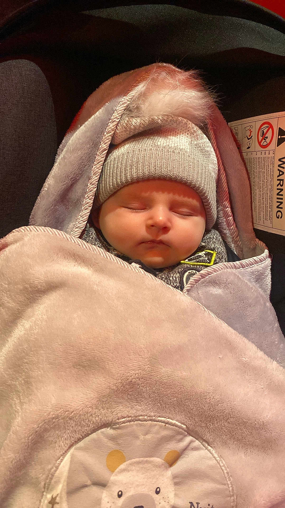 Oliver a rejoint le concours — aidez-le/la à gagner de superbes lots ! baby, sleeping, hat, pom_pom, blanket, bear_design, car_seat, warning_label, cozy, child, infant, face, closed_eyes, warm, soft_texture, cute, bundle, headwear, rest, comfort