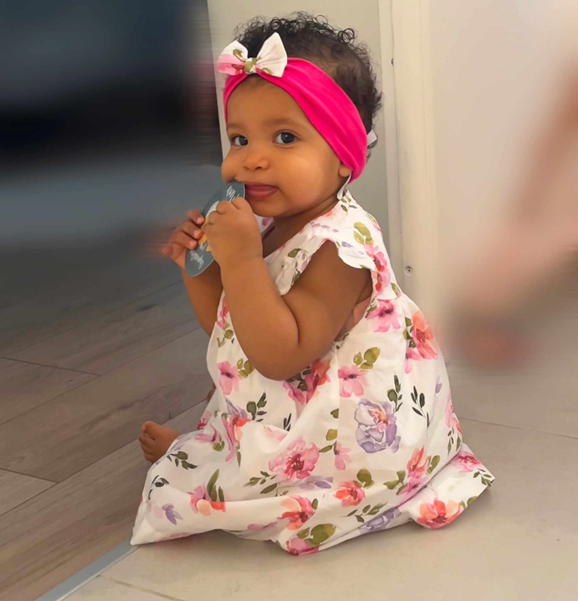 Alma a rejoint le concours — aidez-le/la à gagner de superbes lots ! baby, child, girl, headband, bow, floral_dress, sitting, floor, indoors, curly_hair, cute, playful, chewing, card, portrait, skin, happy, young_child, one_person, closeup