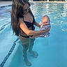Leilani is registered to the contest to win money with this photo: woman, baby, pool, water, bikini, swimming, outdoor, summer, child, holding, people, residential, building, lounge_chair, sunlight, relaxation, family, vacation, casual, daytime