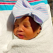 Anijah is registered to the contest to win money with this photo: newborn, baby, sleeping, infant, portrait, close_up, face, bow, hat, swaddled, blanket, white_blanket, striped, pink, blue, indoors, peaceful, cute, resting, photography