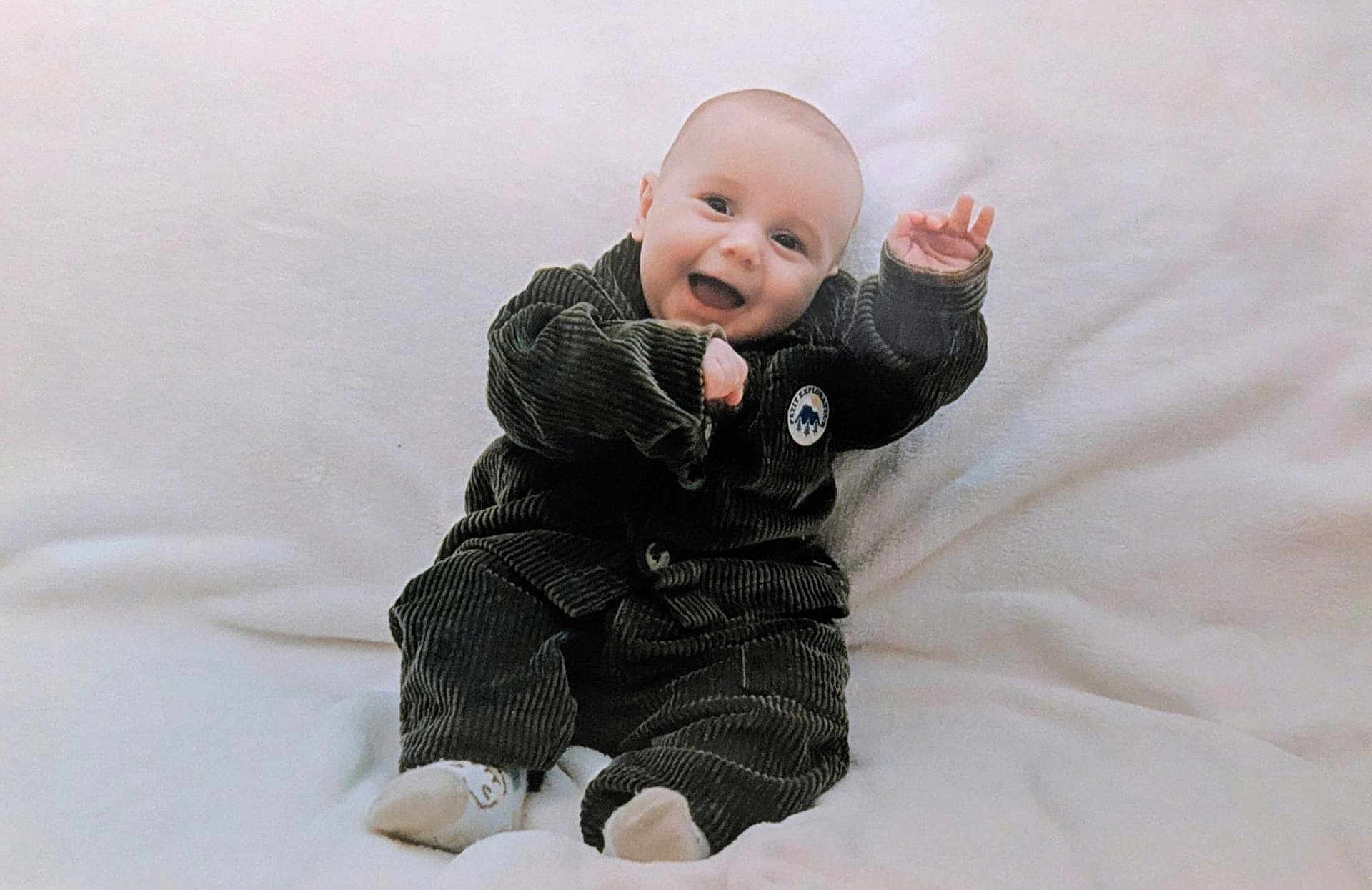 Louis participe au concours pour gagner de l'argent avec cette photo : baby, infant, smiling, corduroy_clothing, sitting, white_blanket, happy, child, cute, portrait, indoors, cozy, soft_texture, small_hands, footwear, young, person, expression, cheerful, candid