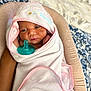 Namylah is registered to the contest to win money with this photo: newborn, baby, wrapped, towel, pink_trim, hood, pacifier, cushion, blanket, blue_pattern, sleepy, infant, cozy, soft, bed, portrait, cute, resting, hand, indoors