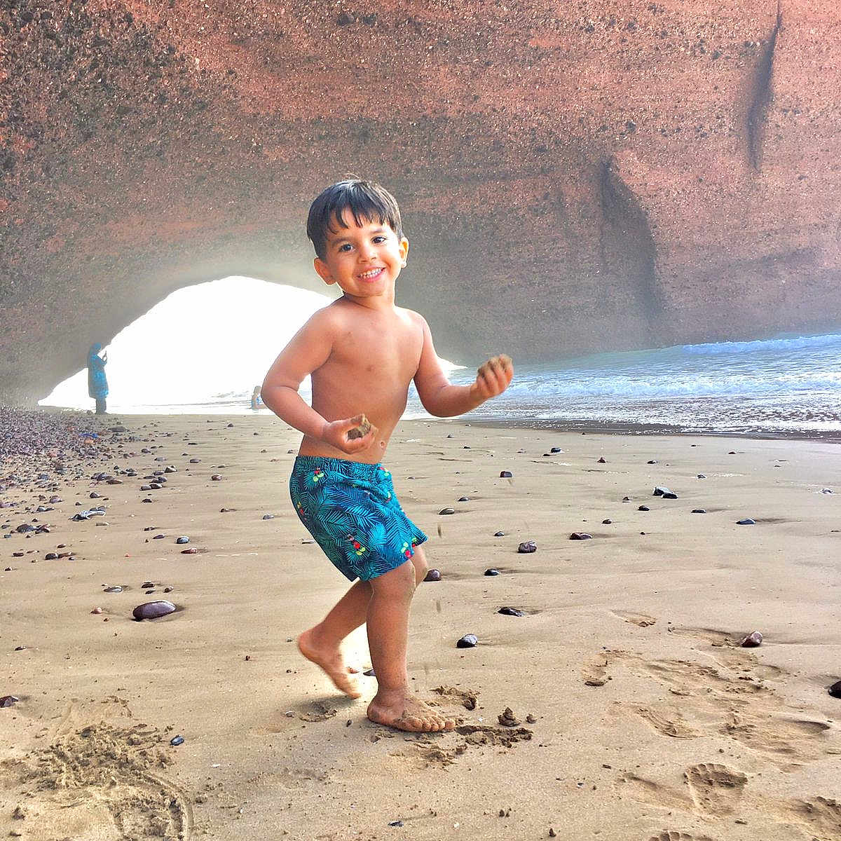 Saif Eddine participe au concours pour gagner de l'argent avec cette photo : barefoot, beach, boy, cave, child, clothing, happy, nature, ocean, outdoor, person, playful, portrait, rocks, sand, shore, smiling, summer, vacation, water