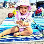 toddler, child, beach, sand, hat, sunhat, striped_towel, polka_dot, playing, happy, smiling, summer, outdoor, toy, bracelet, footwear, clothing, sitting, sunny, vacation