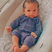 Ezmari is registered to the contest to win money with this photo: baby, infant, curly_hair, purple_onesie, baby_rocker, cushion, wooden_deck, railing, green_grass, barefoot, cute, serious_expression, indoor_outdoor, child, person, baby_clothing, sitting, portrait, cozy, comfort