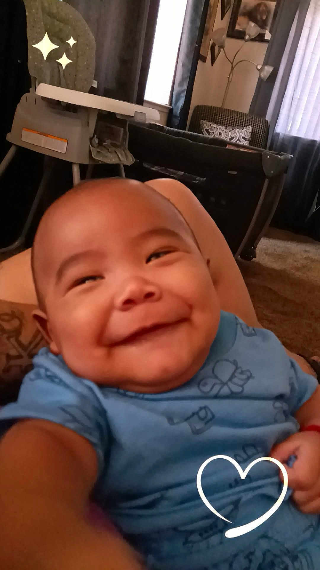 Antonio joined the competition — help win amazing prizes! baby, smiling, blue_clothing, indoor, living_room, furniture, heart_overlay, cute, portrait, child, happy, infant, tattoo, carpet, window, curtains, lamp, playful, selfie, closeup