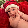 baby, blue_eyes, christmas, christmas_tree, cozy, cute, decorations, face, festive, holiday, holiday_lights, indoors, infant, newborn, portrait, red_blanket, santa_hat, seasonal, soft_skin, warm