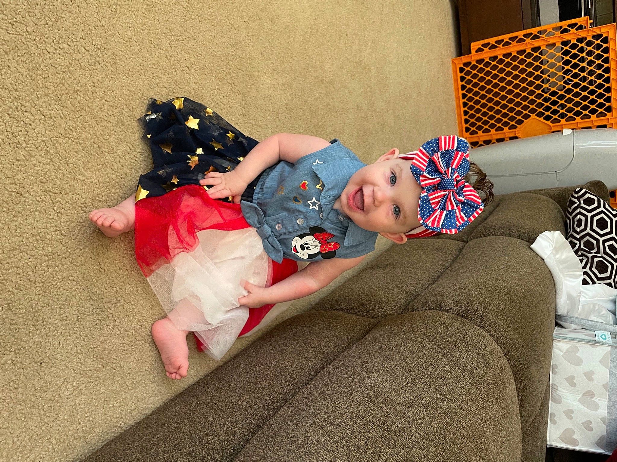 Camille is registered to the contest to win money with this photo: baby, baby_products, baby_toddler_clothing, chair, child, comfort, couch, flooring, fun, headwear, human_leg, lap, linens, living_room, pattern, person, sitting, smile, sofa_bed, thigh