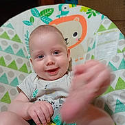 Tyberius is registered to the contest to win money with this photo: baby, child, smiling, foot, hand, face, infant, sitting, baby_chair, pattern, colorful, clothing, cute, indoor, happy, portrait, young_child, playful, animal_illustration, motion_blur