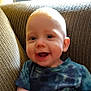 Tyberius is registered to the contest to win money with this photo: baby, child, smiling, face, eyes, mouth, shirt, tie_dye, couch, furniture, indoors, happy, young, person, portrait, sitting, cute, skin, head, expression