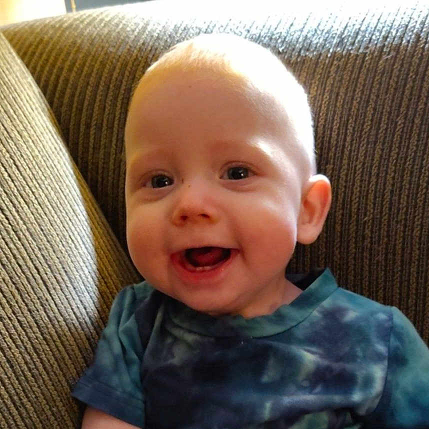 Tyberius is registered to the contest to win money with this photo: baby, child, couch, cute, expression, eyes, face, furniture, happy, head, indoors, mouth, person, portrait, shirt, sitting, skin, smiling, tie_dye, young