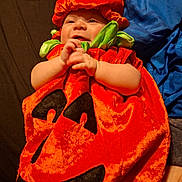 Ryan joined the competition — help win amazing prizes! baby, infant, child, pumpkin_costume, halloween, costume, red, orange, green, blue, leaf, hat, smiling, happy, portrait, lying_down, hands, face, blanket, indoor