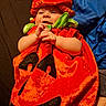 baby, infant, child, pumpkin_costume, halloween, costume, red, orange, green, blue, leaf, hat, smiling, happy, portrait, lying_down, hands, face, blanket, indoor