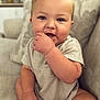 baby, child, infant, couch, sofa, cushion, indoor, portrait, smiling, happy, fingers, hand, face, blue_eyes, short_sleeves, clothing, sitting, furniture, home, cute
