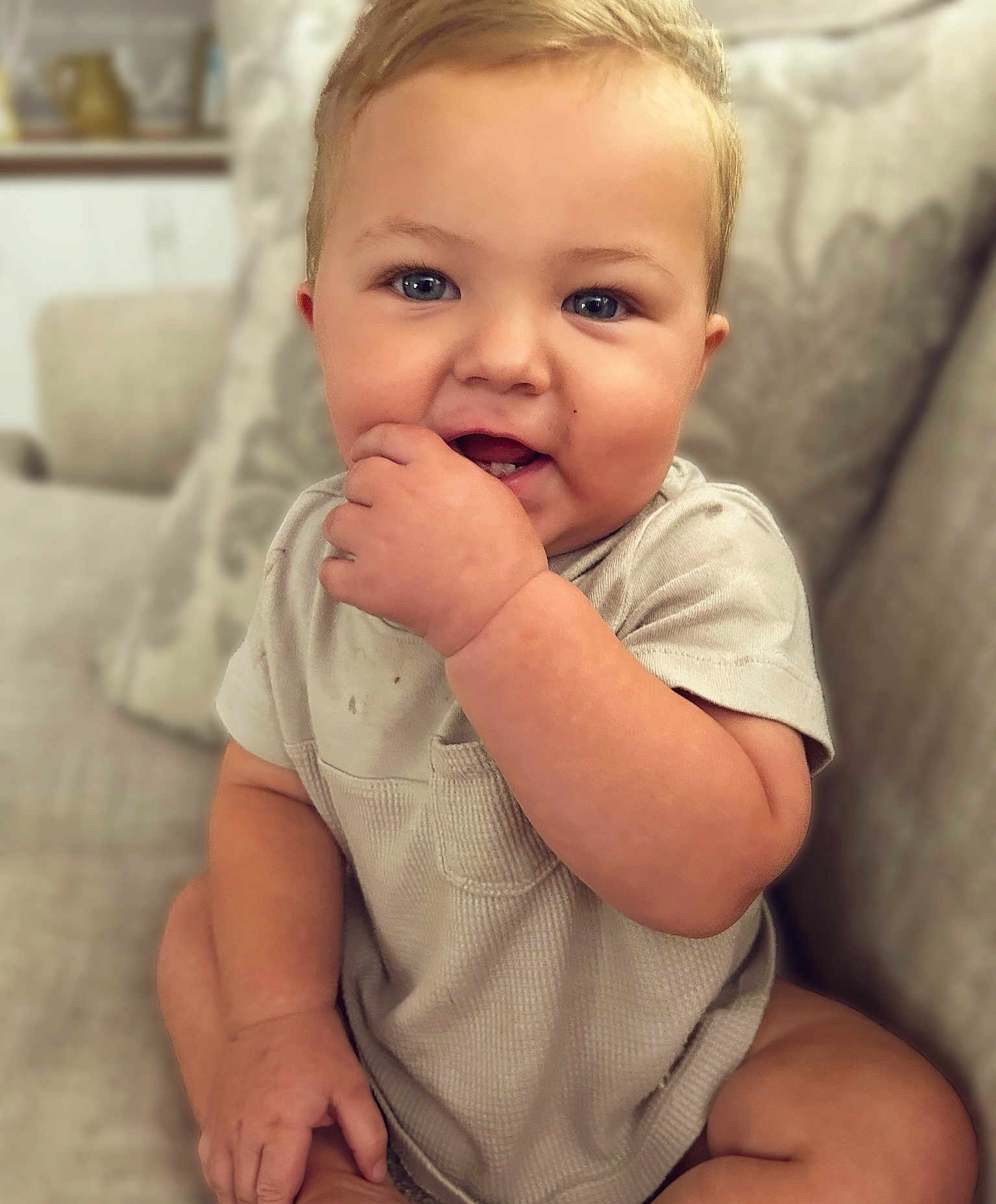 Brooks joined the competition — help win amazing prizes! baby, child, infant, couch, sofa, cushion, indoor, portrait, smiling, happy, fingers, hand, face, blue_eyes, short_sleeves, clothing, sitting, furniture, home, cute