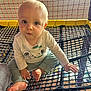 baby, child, net, play_area, indoor, pants, shirt, koala, looking, curious, barefoot, hands, feet, light, yellow, red, black, mesh, infant, young_child