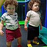 Azure is registered to the contest to win money with this photo: child, toddler, curly_hair, indoor_play_area, playground, dinosaur_shirt, shorts, socks, colorful, netting, play_equipment, standing, two_children, fun, kids, play, smile, casual_clothing, young_children, active