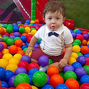 Azure is registered to the contest to win money with this photo: toddler, child, ball_pit, colorful_balls, indoor, play_area, white_shirt, bow_tie, maroon_shorts, plastic_balls, curious, sitting, playful, young_child, person, fun, entertainment, cute, expression, recreation