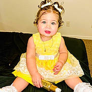 Samara joined the competition — help win amazing prizes! baby, carpet, child, comb, curly_hair, cute, floor, hair_accessory, holding_bottle, indoor, lace_socks, necklace, person, portrait, sitting, smiling, toddler, white_bows, white_shoes, yellow_dress