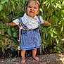 toddler, child, denim, dress, white_shirt, barefoot, garden, plants, greenery, wooden_surface, funny_face, cute, outdoors, sunlight, standing, bracelet, pacifier_clip, nature, small_person, happy