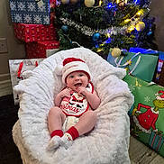 Kanan joined the competition — help win amazing prizes! baby, christmas, holiday, festive, santa_hat, socks, bean_bag, white_fabric, christmas_tree, ornaments, lights, wrapped_presents, gift_bags, grinch, floor, happy, smiling, indoor, celebration, decorations