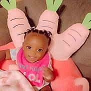 Avaeha joined the competition — help win amazing prizes! baby, child, smiling, braids, bib, blanket, couch, pillow, carrot_pillow, indoors, cute, happy, seated, infant, clothing, home, soft_toy, person, portrait, cozy