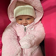 Kiana joined the competition — help win amazing prizes! baby, infant, pink_clothing, hat, smiling, cute, child, warm, cozy, fluffy, jacket, zipper, seated, indoor, face, headwear, portrait, person, bundle, soft