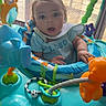 Princeton is registered to the contest to win money with this photo: baby, child, activity_center, toy, bib, shirt, curious, indoor, playtime, colorful, face, expression, window, curtain, floor, foot, plastic, seat, smile, infant