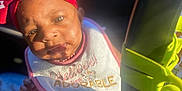 Ariyah is registered to the contest to win money with this photo: baby, infant, headband, red, white, bib, adorable, car_seat, sunlight, shadow, face, eyes, clothing, striped, cute, child, person, indoors, seatbelt, closeup